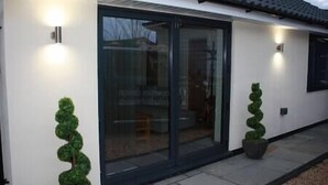 A modern building with large glass doors, potted plants, and exterior lighting.
