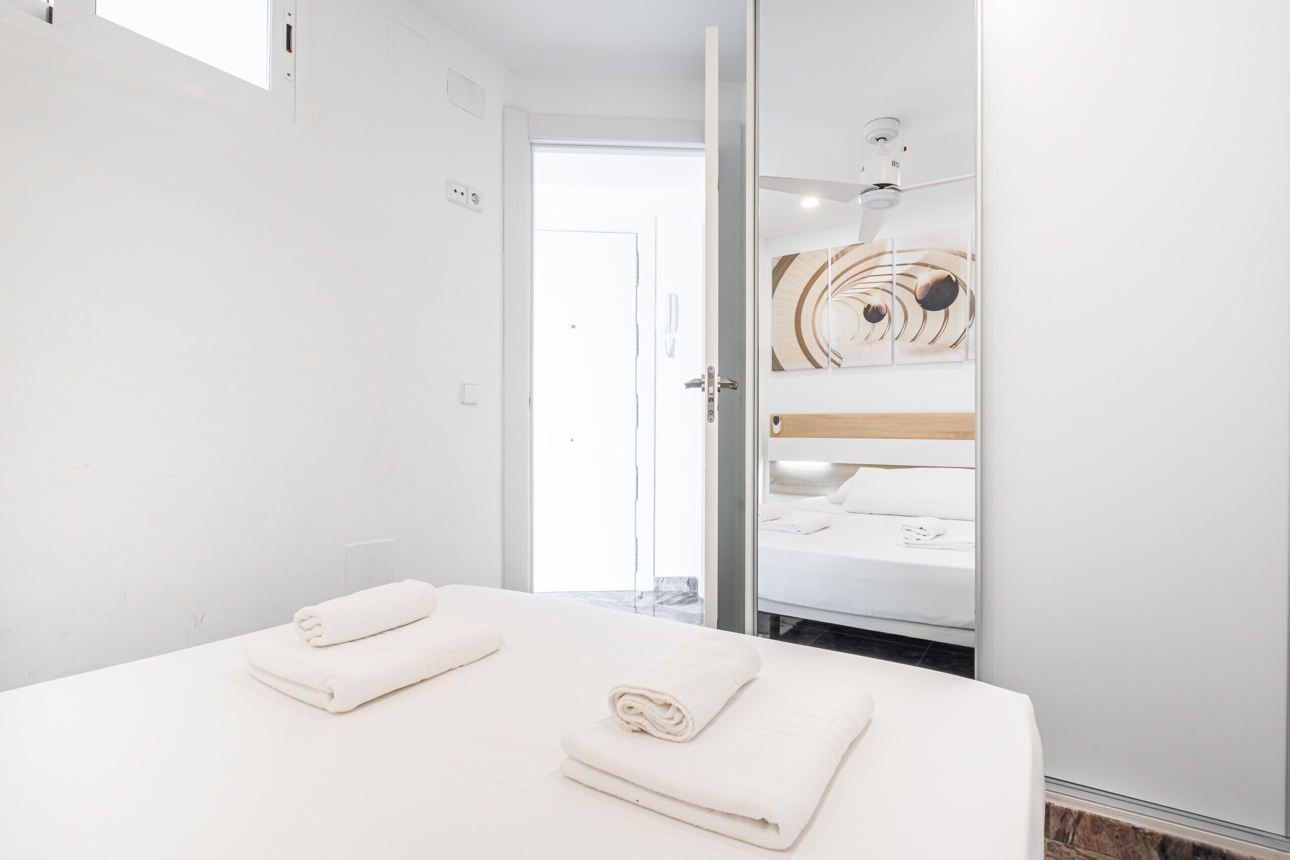 A modern hotel room with a large bed, a wooden headboard, and a view of the bathroom.