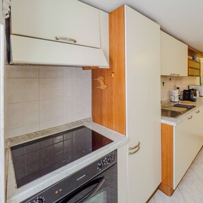 Una cocina compacta con horno empotrado, estufa y microondas.