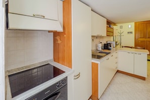 A compact kitchen with white cabinets, a built-in oven, and a countertop with a coffee maker. - Mainetta Sea View Apartment with AC (Vernazza)