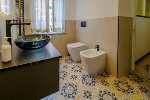 Een badkamer met een moderne wastafel, toilet en vloertegels met een patroon.