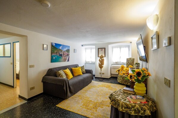 Een woonkamer met een bank, een salontafel, een schilderij en een vaas met bloemen.