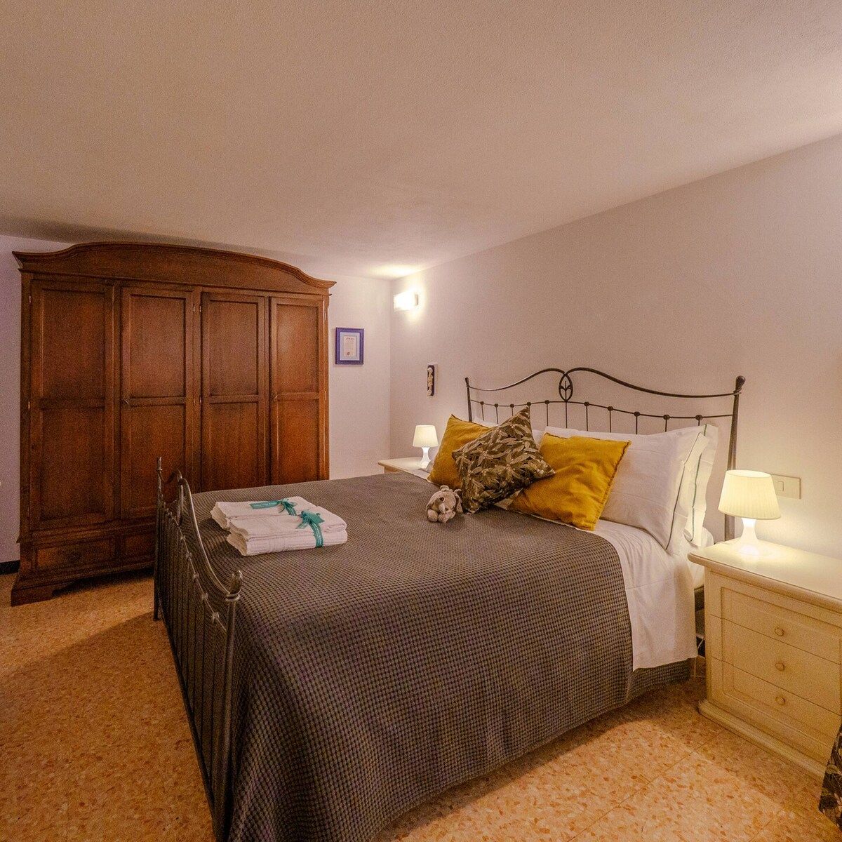 Un dormitorio con cama, armario de madera, mesita de noche con lámpara y luz empotrada en la pared.