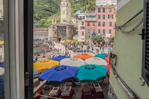 A view of a coastal town with colorful buildings, a clock tower, and a crowded beach area with umbrellas.