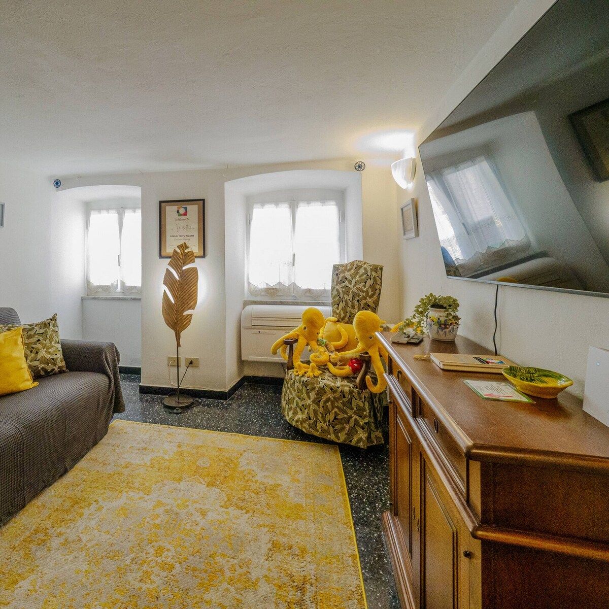 A living room with a sofa, a coffee table, a television, and a decorative plant.