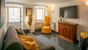 Un salon chaleureux avec un canapé, un fauteuil jaune, un meuble en bois et un téléviseur fixé au mur.