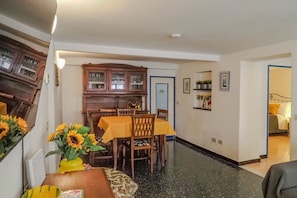 A dining area with a wooden table and chairs, a cabinet with glass doors, and a vase with sunflowers.