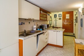 A compact kitchen with white cabinets, a built-in dishwasher, a microwave, and a coffee maker.
