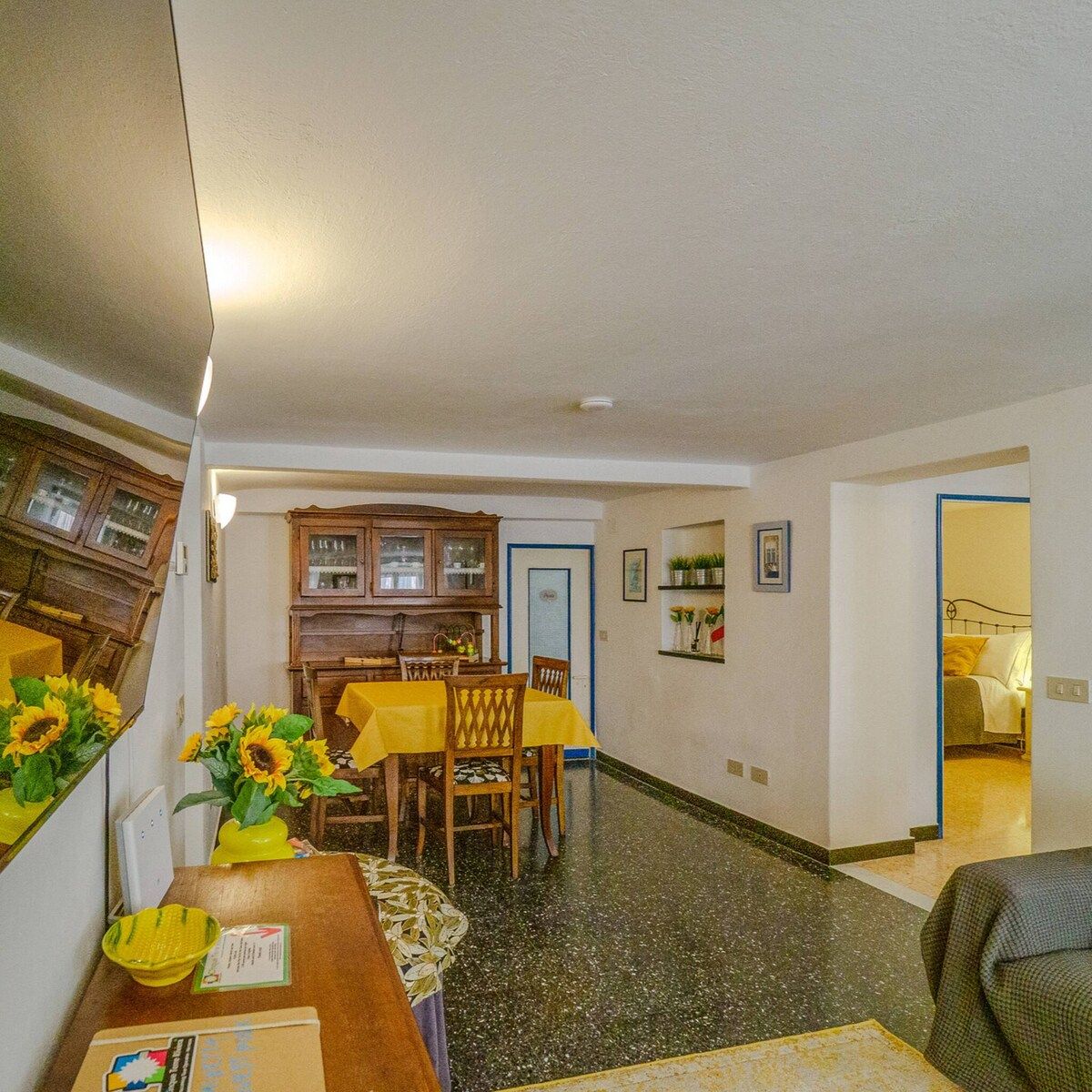 Un comedor con una mesa dispuesta para dos personas, un armario de madera y un pasillo que conduce a un dormitorio.