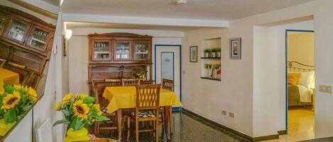 Un comedor con una mesa dispuesta para dos personas, un armario de madera y un pasillo que conduce a un dormitorio.