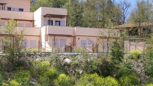 A multi-story building with balconies, surrounded by trees and vegetation.