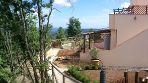 A garden pathway leading to a house with a pergola and a potted plant.