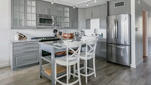 A modern kitchen with grey cabinets, stainless steel appliances, and a central island with stools. - Villa Nautilus, Nautilus on Sapphire Beach (Charlotte Amalie)