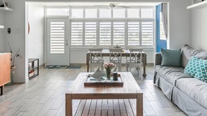 A bright living room with a wooden coffee table, a grey sofa, and a dining area with a table and chairs. - Villa Nautilus, Nautilus on Sapphire Beach (Charlotte Amalie)
