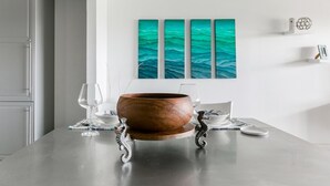A modern dining table with a wooden bowl centerpiece, white chairs, and a teal ocean-themed painting on the wall. - Villa Nautilus, Nautilus on Sapphire Beach (Charlotte Amalie)