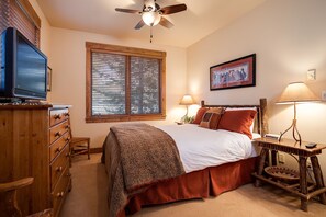 A bedroom with a bed, wooden dresser, ceiling fan, window with blinds, bedside lamps, and a framed picture on the wall. - TL2208 | Elegant and Accommodating | Bring the Whole Family | Winter Shuttle (Steamboat Springs)
