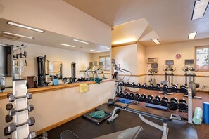 Une salle de sport équipée de divers appareils d’exercice, notamment des tapis de course, des appareils de musculation et des haltères.