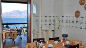 Ein Essbereich mit Blick auf das Meer und die Berge, ausgestattet mit Tisch, Tellern, Tassen und einer Kaffeekanne.