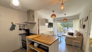 A modern kitchen with a wooden island, white cabinets, and hanging kitchen utensils. - MIRADORBEACH-1ºlínea Playa-Wifi y Garaje Gratis. (Calpe / Calp)