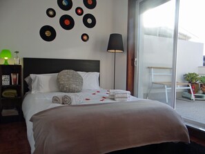 A neatly made bed with a grey pillow, a bedside lamp, and a wall decorated with vinyl records. - Alegria Apartment Downtown Porto, 2- 5 pax (Porto)