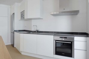 A modern kitchen with white cabinetry, a Bosch oven, and a stainless steel range hood.