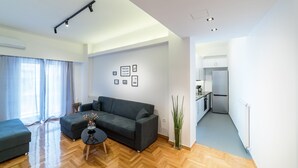 A modern living room with a grey sofa, a small round table, and a vase of flowers. - Modern design apartment near Acropolis (Athina)
