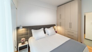 A modern bedroom with a large bed, bedside lamps, and a wardrobe. - Modern design apartment near Acropolis (Athina)