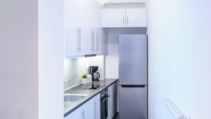 A modern kitchen with white cabinets, a stainless steel refrigerator, a coffee maker, and a dishwasher. - Modern design apartment near Acropolis (Athina)