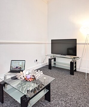 Relax in this stylish living room with a flat-screen TV, glass coffee table, and laptop workspace.