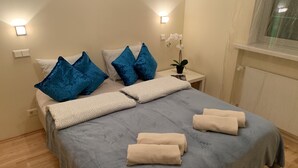 A neatly made bed with blue and beige pillows, a grey duvet, and rolled towels. - Ilmarine Apartment in city center (Tallinn)