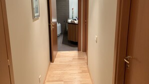 A narrow hallway with wooden flooring leading to a bathroom with a sink and towel rack. - Ilmarine Apartment in city center (Tallinn)