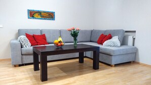 A modern living room with a grey sectional sofa, a dark wooden coffee table, and a vase with flowers. - Ilmarine Apartment in city center (Tallinn)