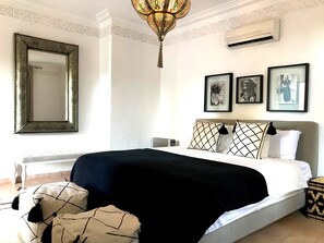 A bedroom with a large bed, a decorative mirror, and three framed pictures on the wall. - Palais Souad (Marrakech)