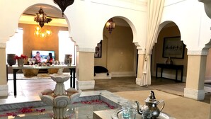Un hall d’entrée spacieux avec un sol en marbre, une fontaine centrale et un coin salon équipé d’un téléviseur.