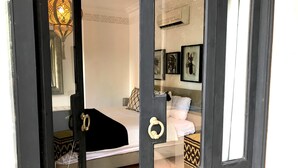 Une chambre à coucher comprenant un lit, une table de chevet, un miroir et un climatiseur fixé au mur.