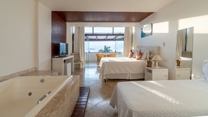 A modern hotel room with a large bed, a separate sitting area with a chair and table, a bathtub, and a balcony with a view. - Eny Boutique Hotel (Búzios)