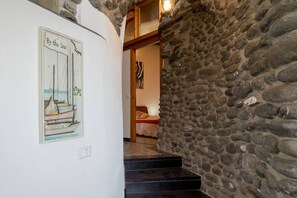 A stone wall, a staircase, and a framed picture of a sailboat on a wall.