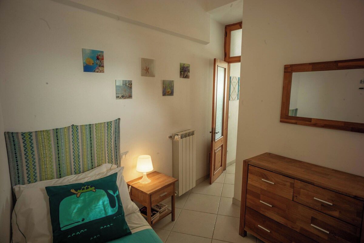 Une chambre à coucher comprenant un lit, une table de chevet, une lampe, une commode et une porte donnant sur une autre pièce.