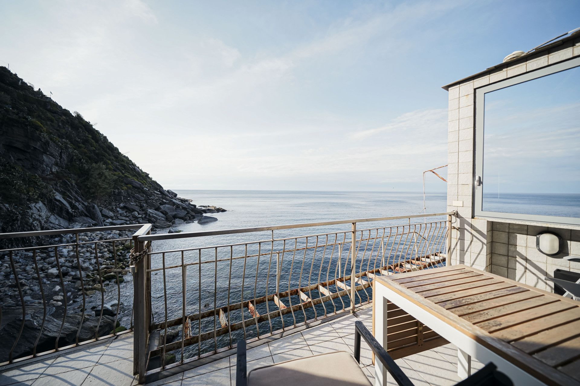 A balcony with a view of the sea and rocky coastline.