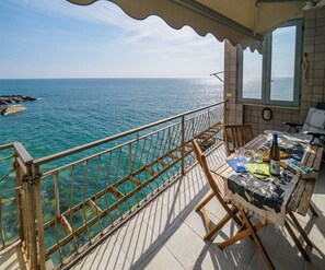 A balcony with a view of the sea, a table with a bottle, glasses, and a menu.