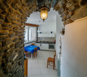 Une cuisine avec des meubles blancs, une table bleue et un arc en pierre.