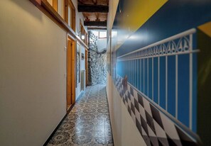 A hallway with patterned floor tiles, a stone wall, and a blue wall with a decorative railing.
