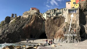 Une ville côtière dotée d’une forteresse historique en pierre, de bâtiments aux couleurs vives et d’une plage rocheuse.