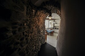Un arc en pierre mène à un espace dédié à la salle à manger, où se trouvent une table et des chaises.
