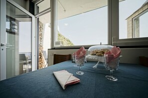Une table dressée avec un verre transparent, une serviette pliée et un verre contenant un dessert.