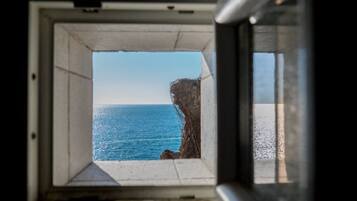 A window with a view of the ocean and a rocky cliff.