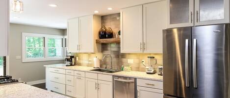 A modern kitchen with white cabinets, stainless steel appliances, and a built-in dishwasher.