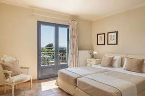 A bedroom with a double bed, a chair, a nightstand, a lamp, and two framed pictures on the wall.