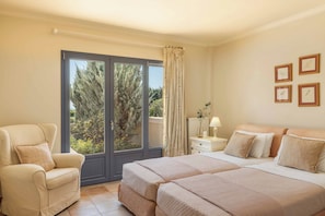 A bedroom with a bed, a chair, a nightstand, and a window with curtains.