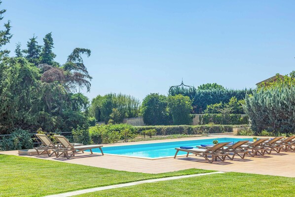 A swimming pool with lounge chairs and a clear sky.